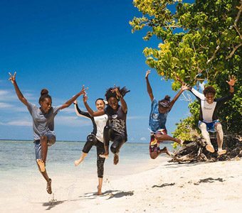 Dive Munda's dive instructor Euna with students on beach celebrating